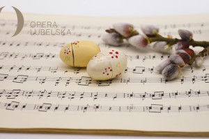 obraz przedstawia zdobione jajka wielkanocne i gałązki bazi na tle nut